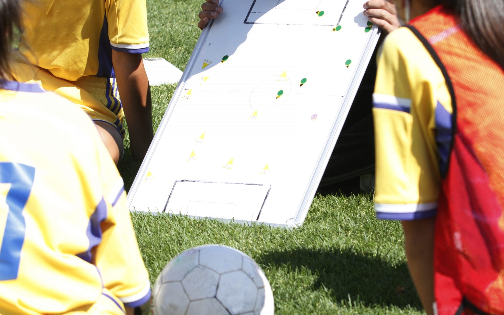 ボードを使ってサッカーのフォーメーションを指示する写真